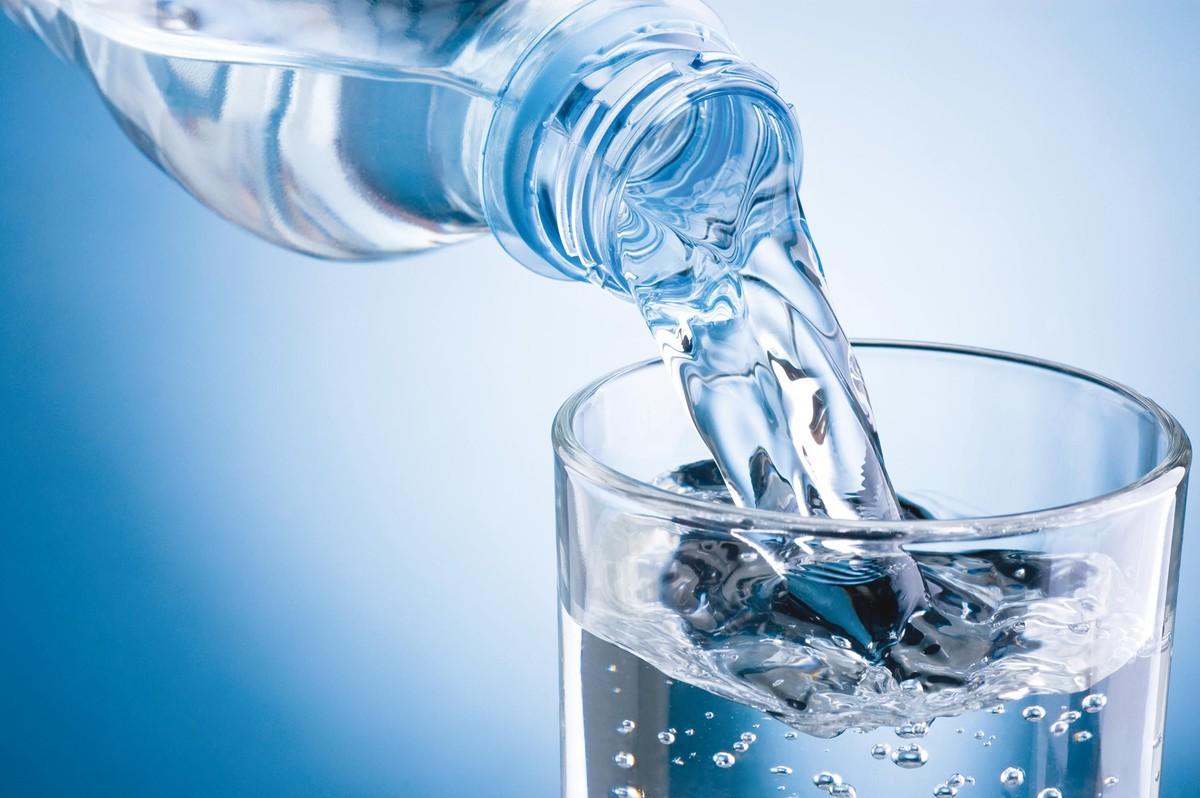 Une bouteille d'eau en train d'être versée dans un verre.