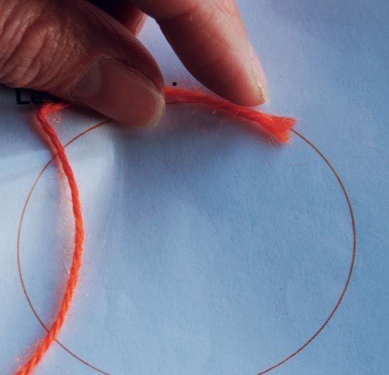 Photographie d'un cerle dessiné sur une feuille et d'une main tenant un fil rouge 