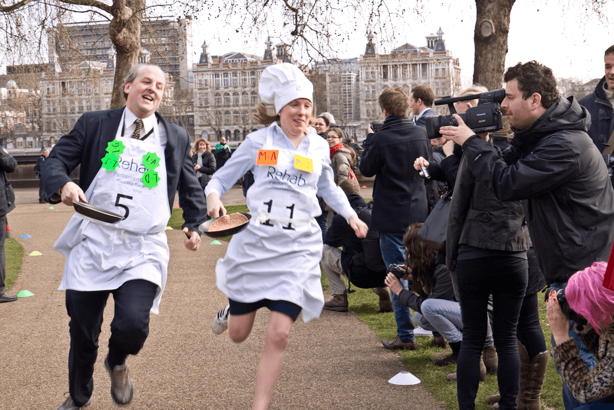 Photographie de personnes déguisées en train de courir pour le Pancake race