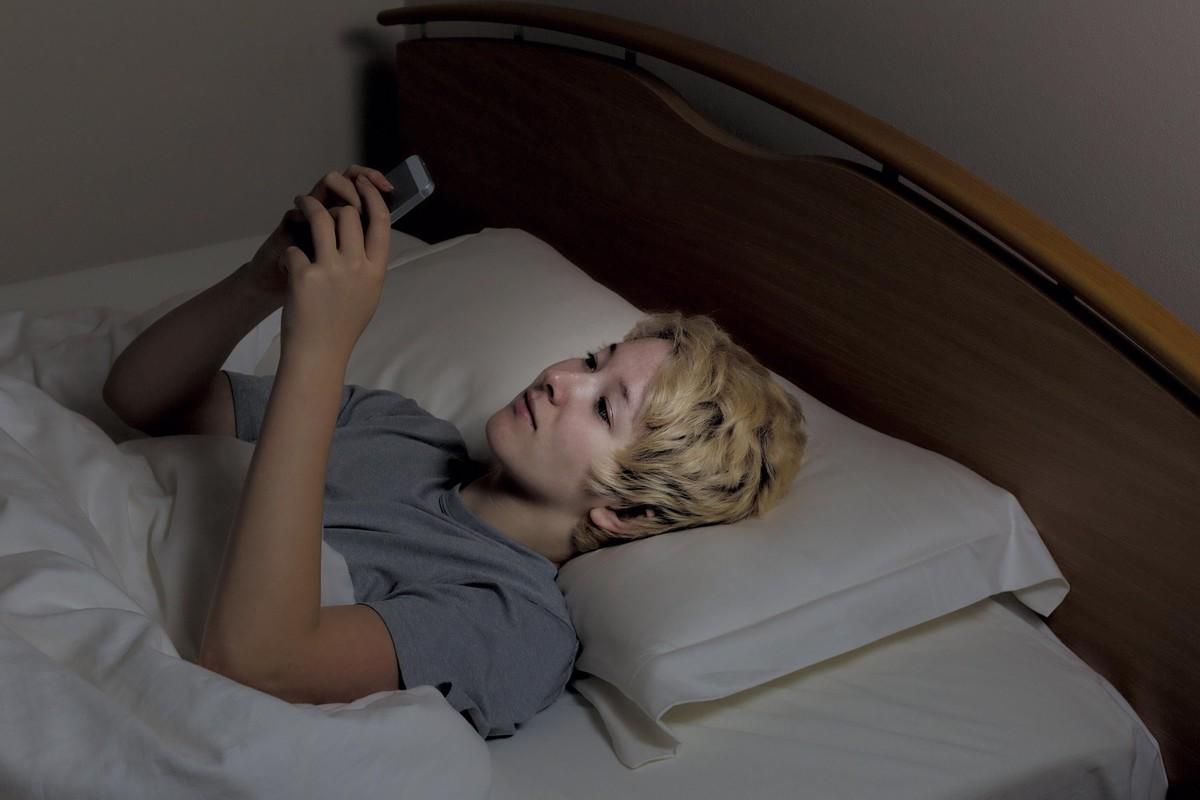 Une adolescente utilisant son téléphone portable dans son lit.